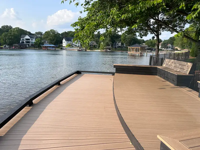 Curved composite deck edge on a lakefront, black aluminum railing following the arc out over open water