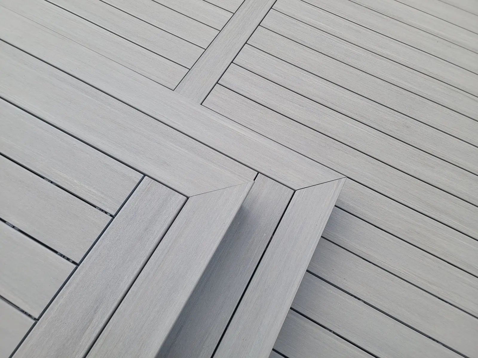 Gray composite deck boards with mitered picture-frame border detail, built by Higher Ground Outdoor Living
