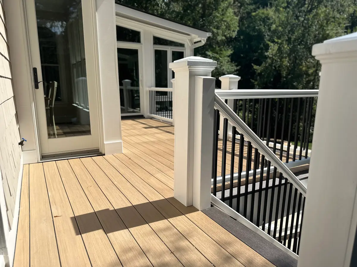 Composite deck with white post sleeves and black aluminum balusters outside a screened porch, Lake Norman area