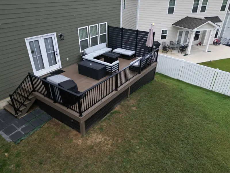 Aerial of the deck showing black railing, privacy screen, and the stair down to the yard