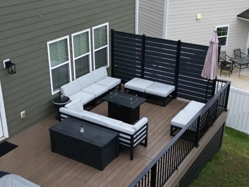 Ground-level view of the seating area, black slat privacy screen, and closed patio umbrella