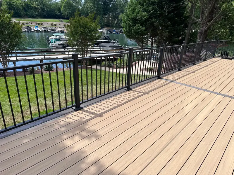 Composite deck with black aluminum railing overlooking a lake cove and boat slips