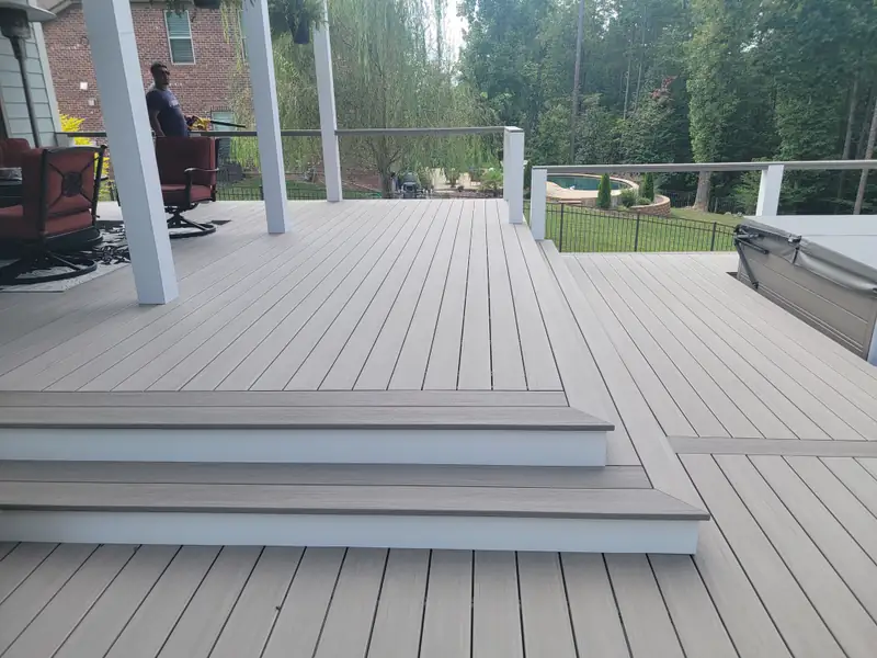 Wide gray composite deck with broad cascading steps, white columns, and a covered seating area