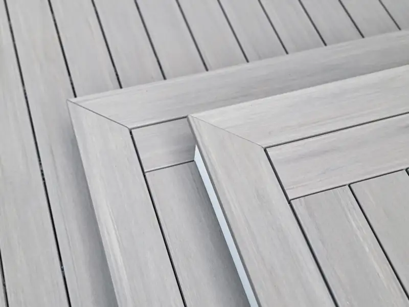 Close detail of mitered picture-frame border boards meeting at a corner on gray composite decking