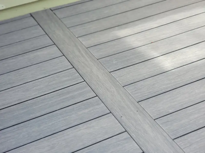 Gray composite decking with a contrasting darker inlay board running diagonally across the field