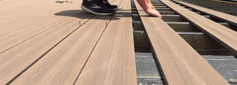 Replacement composite deck boards being laid over existing joists during a deck rebuild