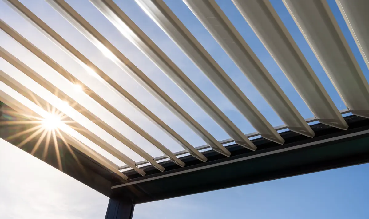 Motorized louvered pergola roof with the louvers angled open against a blue sky